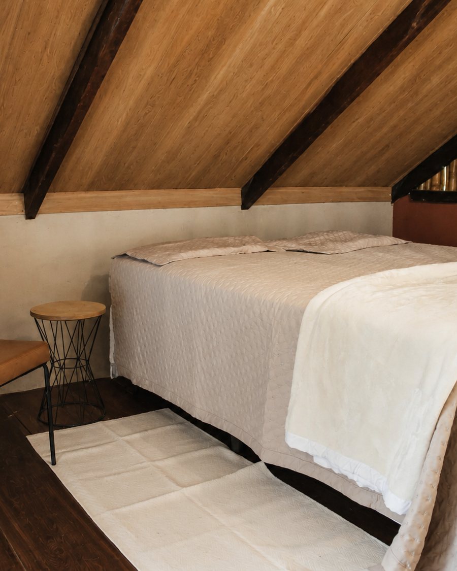 Quarto com cama arrumada sob o telhado