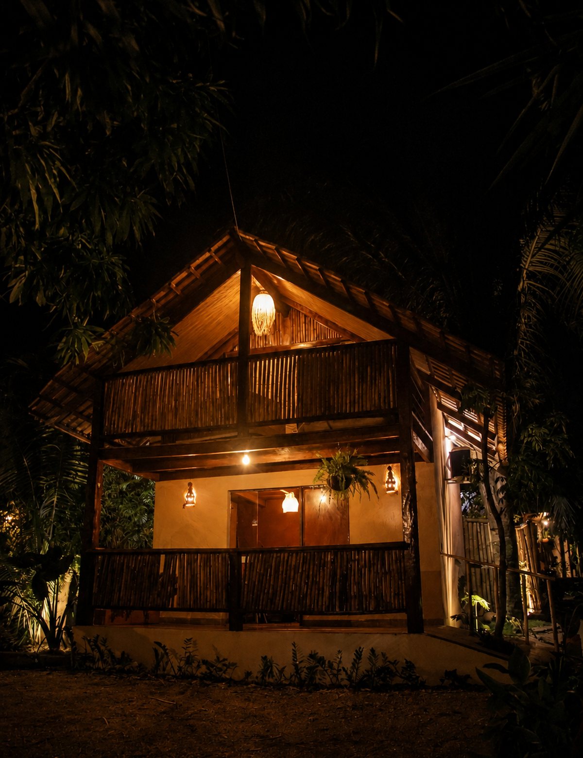 Chalé de bambu iluminado à noite, cercado de mata